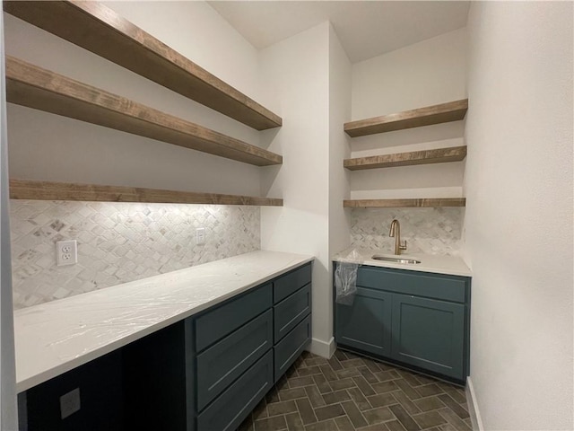 bar with decorative backsplash, a sink, and baseboards