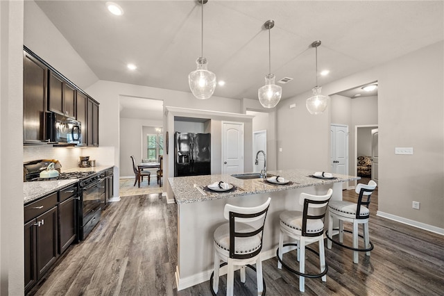 3860 Still Creek Loop, College Station, TX 77845 - kitchen with black appliances, a sink, dark wood finished floors, dark brown cabinetry, and an island with sink