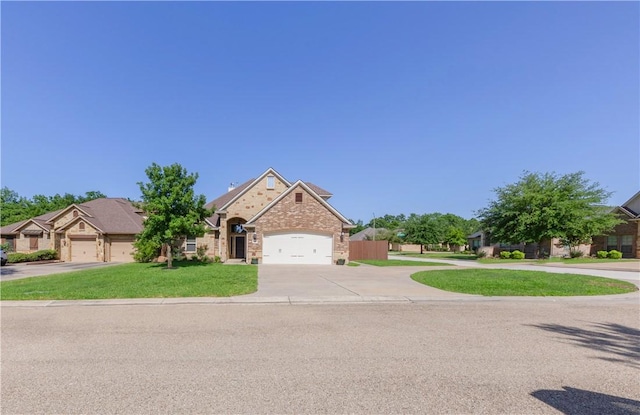 traditional home with concrete driveway, an attached garage, a front yard, and brick siding