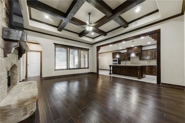unfurnished living room with ceiling fan, baseboards, wood finished floors, coffered ceiling, and beamed ceiling