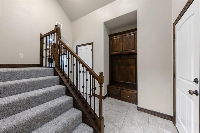 stairs with lofted ceiling, baseboards, and tile patterned flooring
