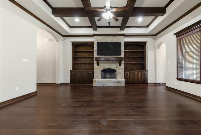 unfurnished living room with arched walkways, a ceiling fan, baseboards, coffered ceiling, and beam ceiling
