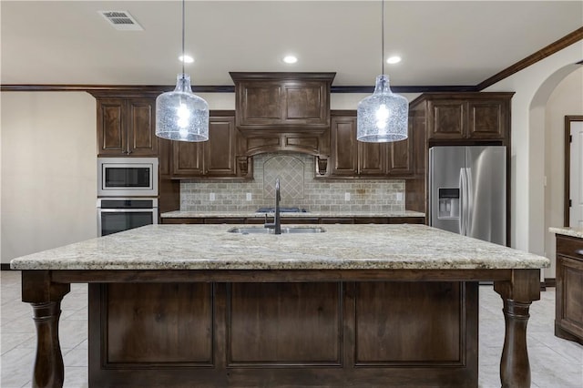 kitchen with stainless steel appliances, light tile patterned flooring, arched walkways, dark brown cabinetry, and backsplash