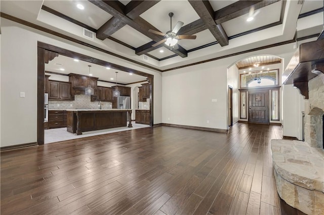 unfurnished living room featuring arched walkways, coffered ceiling, baseboards, wood finished floors, and ceiling fan