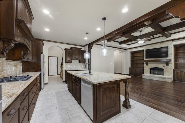 kitchen featuring a sink, arched walkways, a ceiling fan, stainless steel appliances, and open floor plan