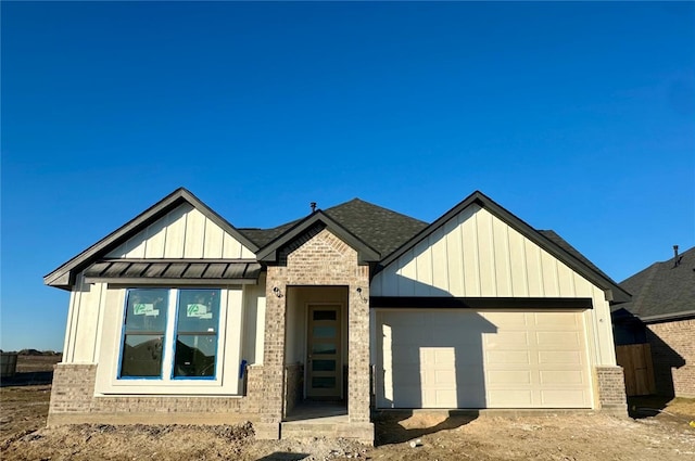 view of front of property with board and batten siding, a standing seam roof, brick siding, and a garage