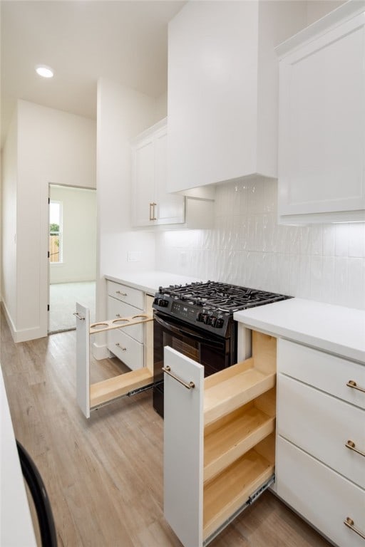 2802 Spector Dr, Bryan, TX 77808 - kitchen with black gas stove, white cabinetry, light countertops, and decorative backsplash