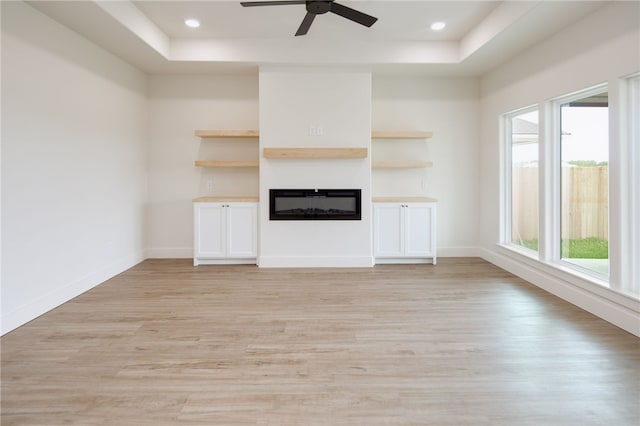 2802 Spector Dr, Bryan, TX 77808 - unfurnished living room featuring a tray ceiling, a glass covered fireplace, light wood-style flooring, ceiling fan, and recessed lighting