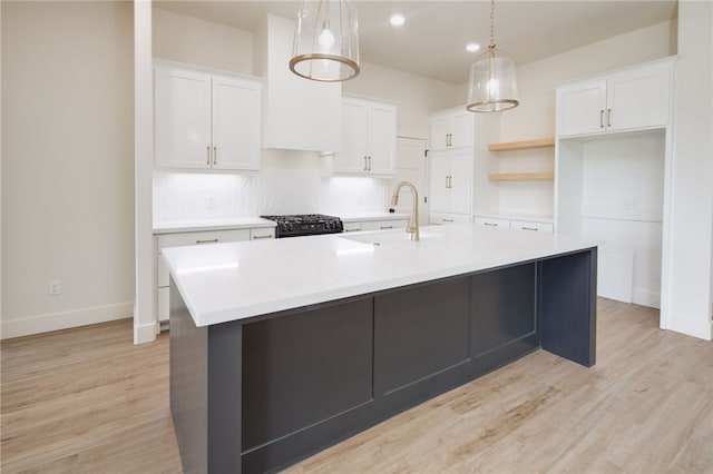 2802 Spector Dr, Bryan, TX 77808 - kitchen with a sink, a kitchen island with sink, white cabinets, light wood-style floors, and recessed lighting