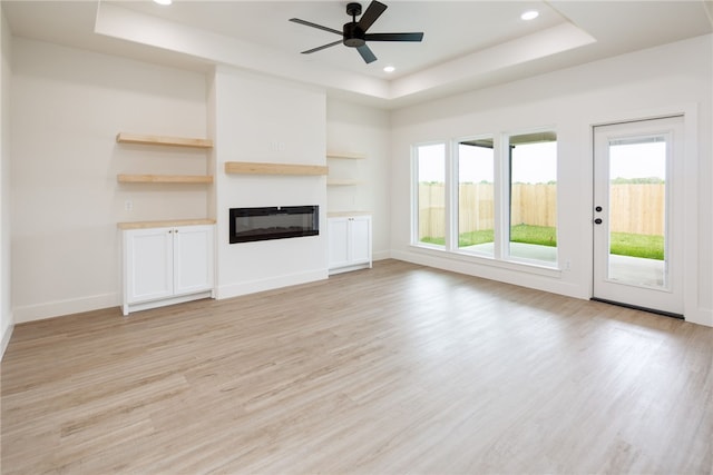 2802 Spector Dr, Bryan, TX 77808 - unfurnished living room featuring a tray ceiling, light wood-style floors, a glass covered fireplace, ceiling fan, and recessed lighting