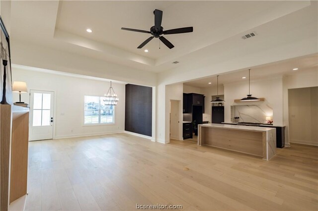 kitchen featuring pendant lighting, ceiling fan with notable chandelier, light hardwood / wood-style flooring, and a kitchen island