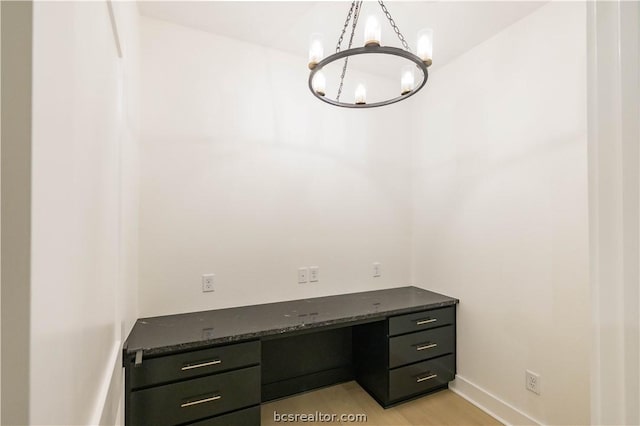 unfurnished office featuring light hardwood / wood-style flooring and an inviting chandelier