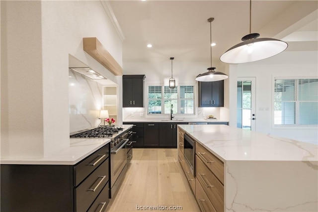 kitchen featuring light stone counters, plenty of natural light, stainless steel appliances, sink, and hanging light fixtures