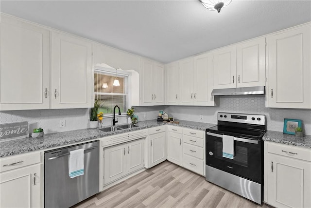 907 Barnhill St, Brenham, TX 77833 - kitchen featuring stainless steel appliances, under cabinet range hood, white cabinets, light wood-style floors, and light stone countertops