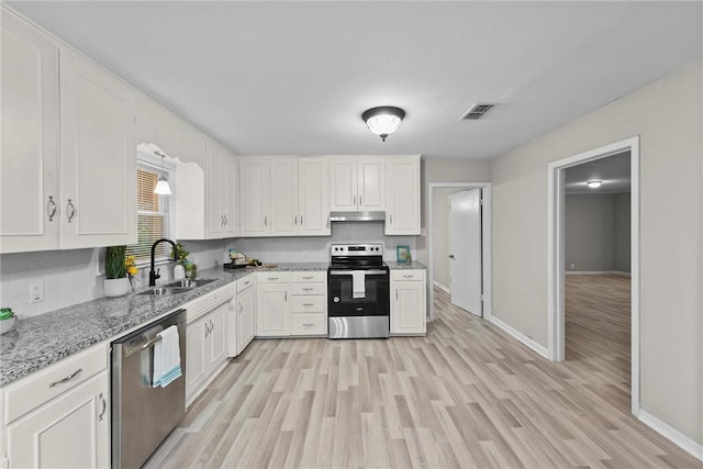907 Barnhill St, Brenham, TX 77833 - kitchen with stainless steel appliances, under cabinet range hood, white cabinets, and light wood-type flooring