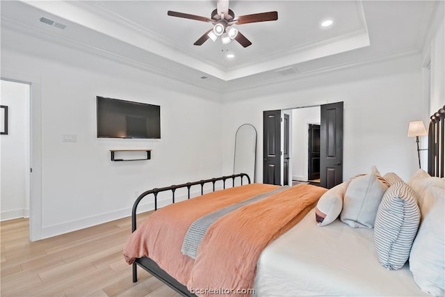 bedroom with a raised ceiling, light hardwood / wood-style flooring, ceiling fan, and ornamental molding