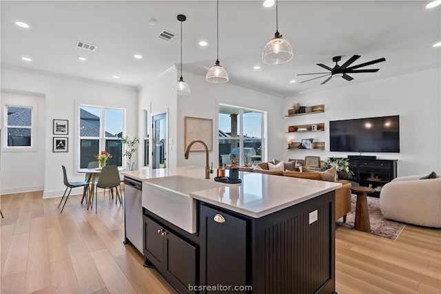 kitchen featuring pendant lighting, stainless steel dishwasher, ceiling fan, light wood-type flooring, and an island with sink