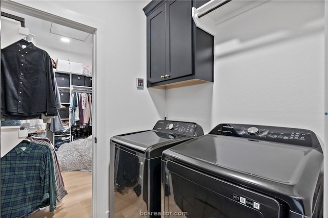 clothes washing area with cabinets, wood-type flooring, and separate washer and dryer