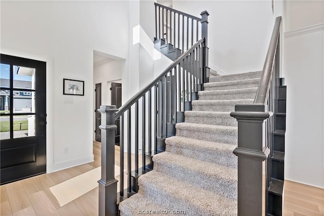 entrance foyer with hardwood / wood-style floors and a towering ceiling