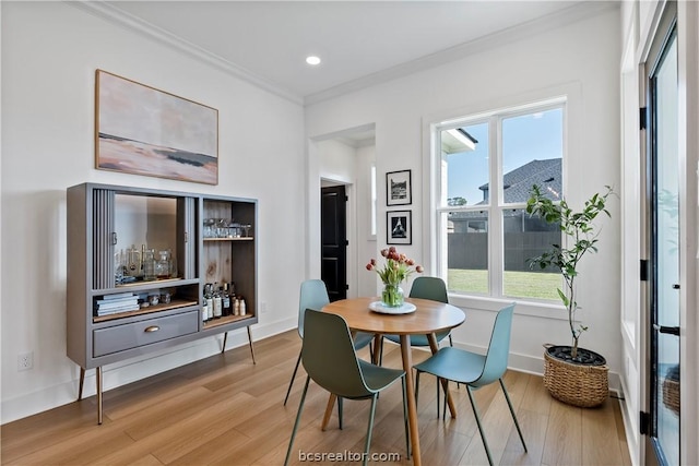 dining room with light hardwood / wood-style floors and crown molding