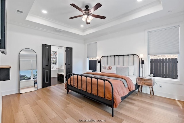 bedroom featuring a tray ceiling, ceiling fan, light hardwood / wood-style floors, and ornamental molding