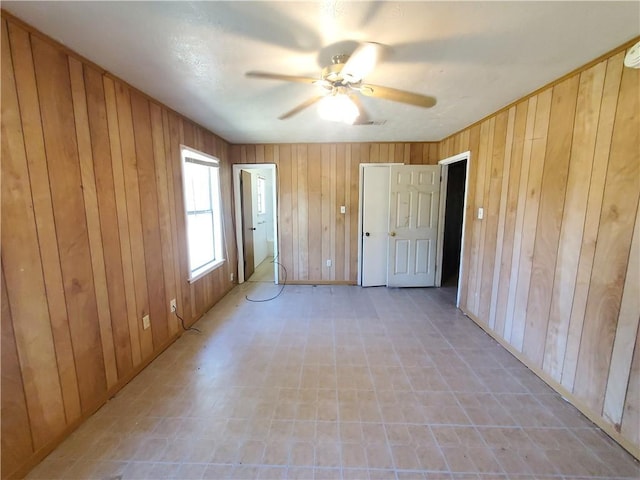 unfurnished room featuring ceiling fan and wood walls