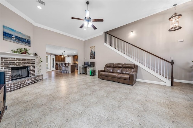 living area with crown molding, baseboards, stairs, ceiling fan with notable chandelier, and a fireplace