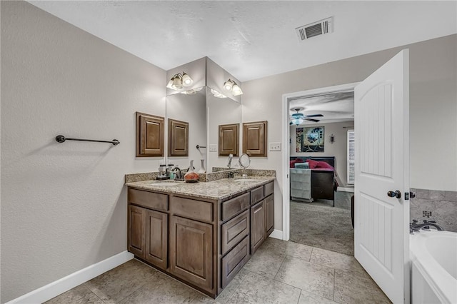 full bath featuring visible vents, double vanity, a sink, a bath, and connected bathroom