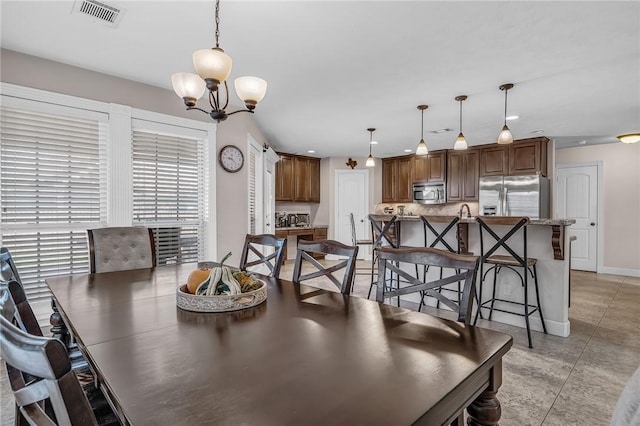 dining area with baseboards, visible vents, and a chandelier