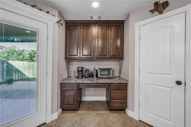 bar featuring visible vents, baseboards, a toaster, light tile patterned floors, and built in desk