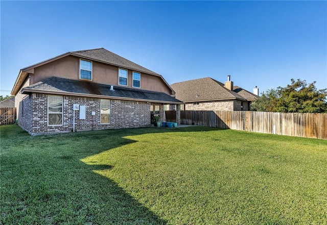 rear view of house featuring stucco siding, a lawn, and a fenced backyard