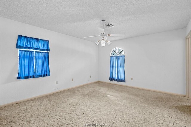 empty room with carpet flooring, ceiling fan, and a textured ceiling