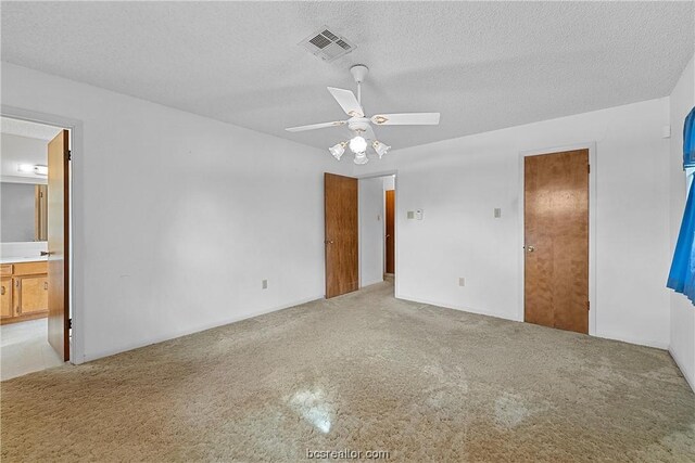 unfurnished bedroom with ceiling fan, a textured ceiling, and ensuite bath