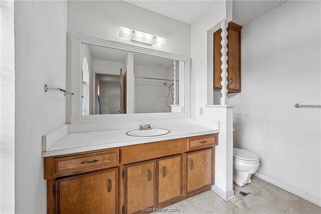 bathroom with vanity, tile patterned flooring, toilet, a textured ceiling, and walk in shower