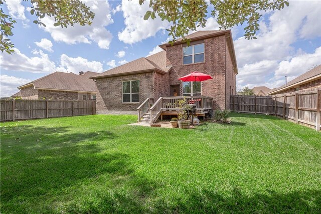 rear view of property featuring a wooden deck and a lawn