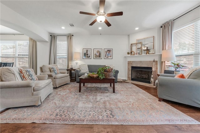 living room featuring a tiled fireplace, a healthy amount of sunlight, hardwood / wood-style floors, and ceiling fan