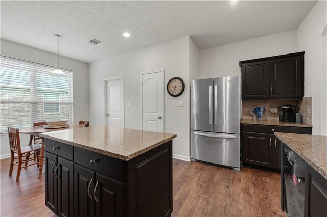 kitchen with stainless steel refrigerator, dark hardwood / wood-style floors, black dishwasher, a kitchen island, and pendant lighting