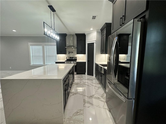 kitchen featuring pendant lighting, a spacious island, wall chimney exhaust hood, stainless steel appliances, and a chandelier