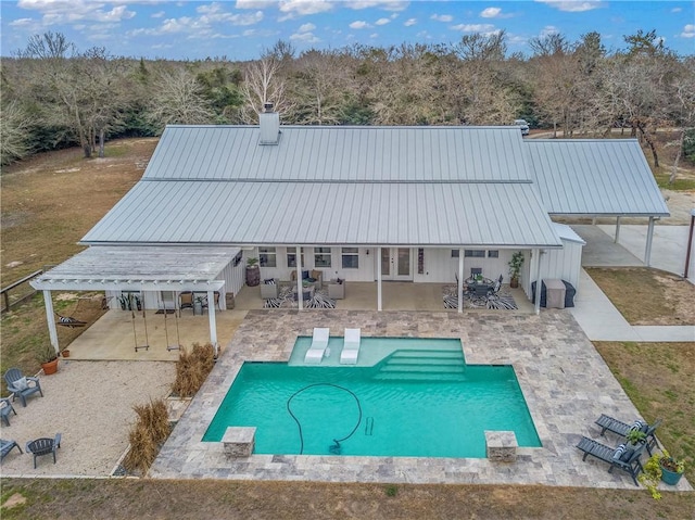 rear view of property featuring a chimney, metal roof, french doors, a patio area, and outdoor dining space