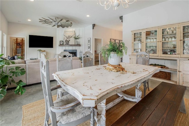 dining area with concrete flooring, recessed lighting, a fireplace, and an inviting chandelier