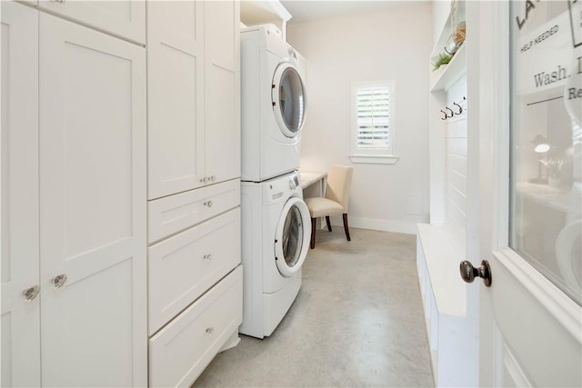 laundry room featuring stacked washing maching and dryer, baseboards, and laundry area