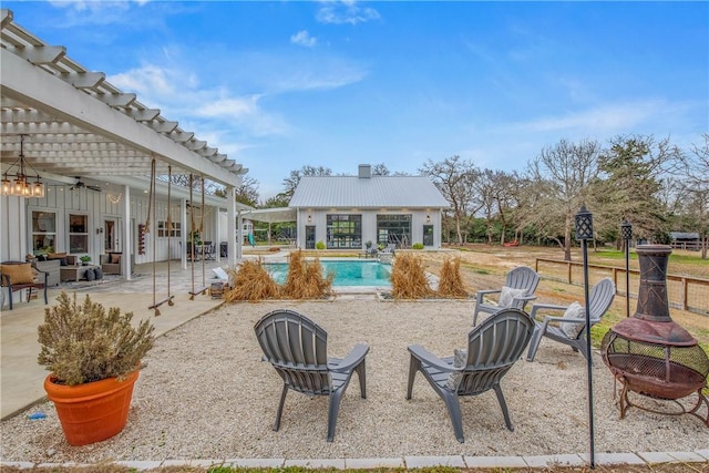 view of patio featuring a fire pit, a pergola, and an outdoor pool