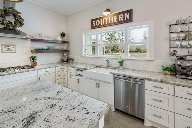 kitchen with appliances with stainless steel finishes, white cabinetry, a sink, and backsplash