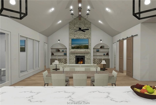 living room featuring built in shelves, ceiling fan with notable chandelier, a barn door, high vaulted ceiling, and a fireplace