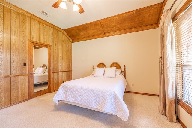 bedroom featuring ceiling fan, light carpet, crown molding, lofted ceiling, and wooden walls