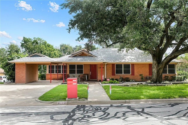 ranch-style home with driveway, a shingled roof, a front lawn, and brick siding