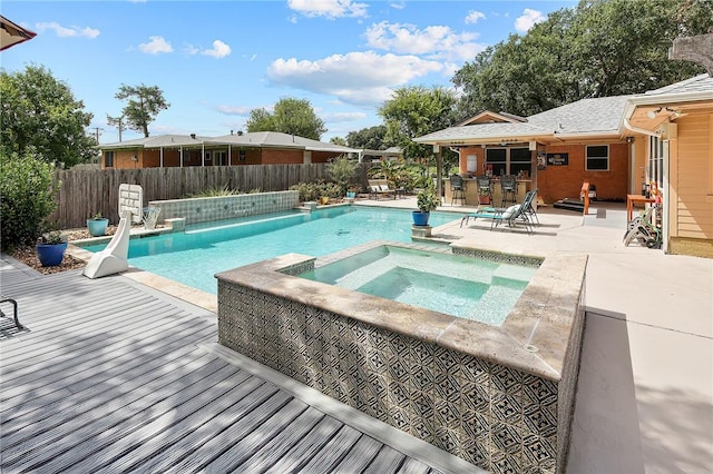 1013 Winding Rd, College Station, TX 77840 - view of swimming pool featuring a pool with connected hot tub, fence, a wooden deck, and a patio
