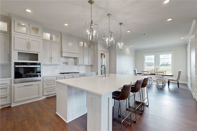 7844 Mathis Creek Dr, Bryan, TX 77808 - kitchen featuring a sink, light countertops, stainless steel oven, custom range hood, and a center island with sink