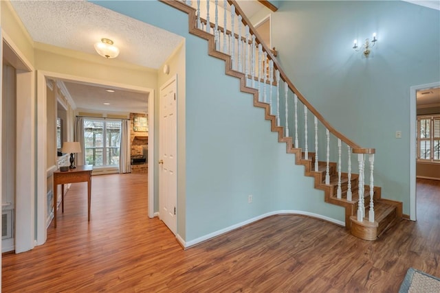 stairs with ornamental molding, plenty of natural light, hardwood / wood-style floors, and a textured ceiling