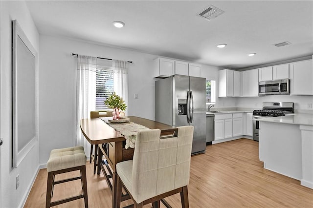 317 Riverwood Village Ln, Sealy, TX 77474 - kitchen featuring stainless steel appliances, a sink, light wood-type flooring, white cabinets, and recessed lighting